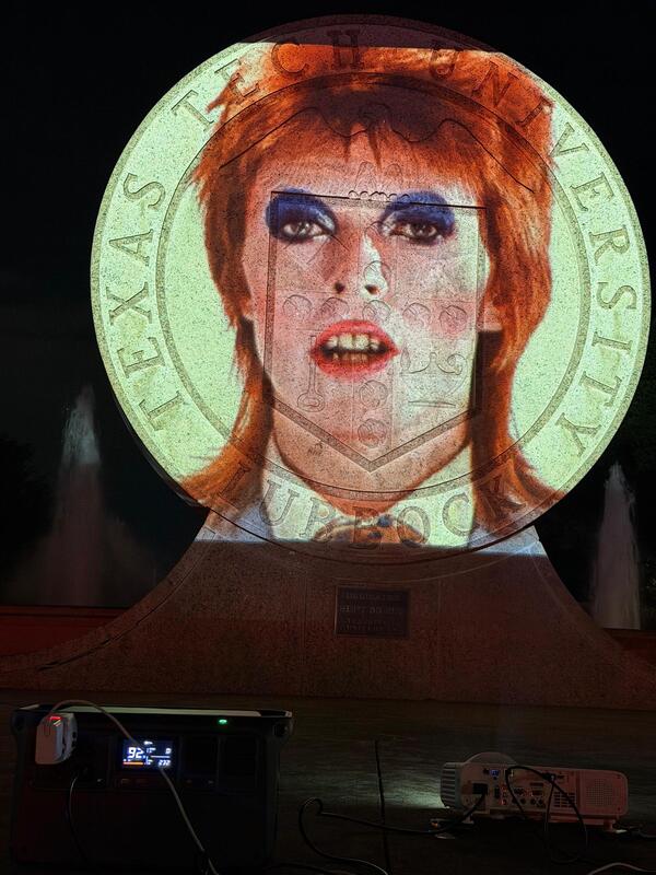 An image of David Bowie’s face projected onto the Texas Tech seal.